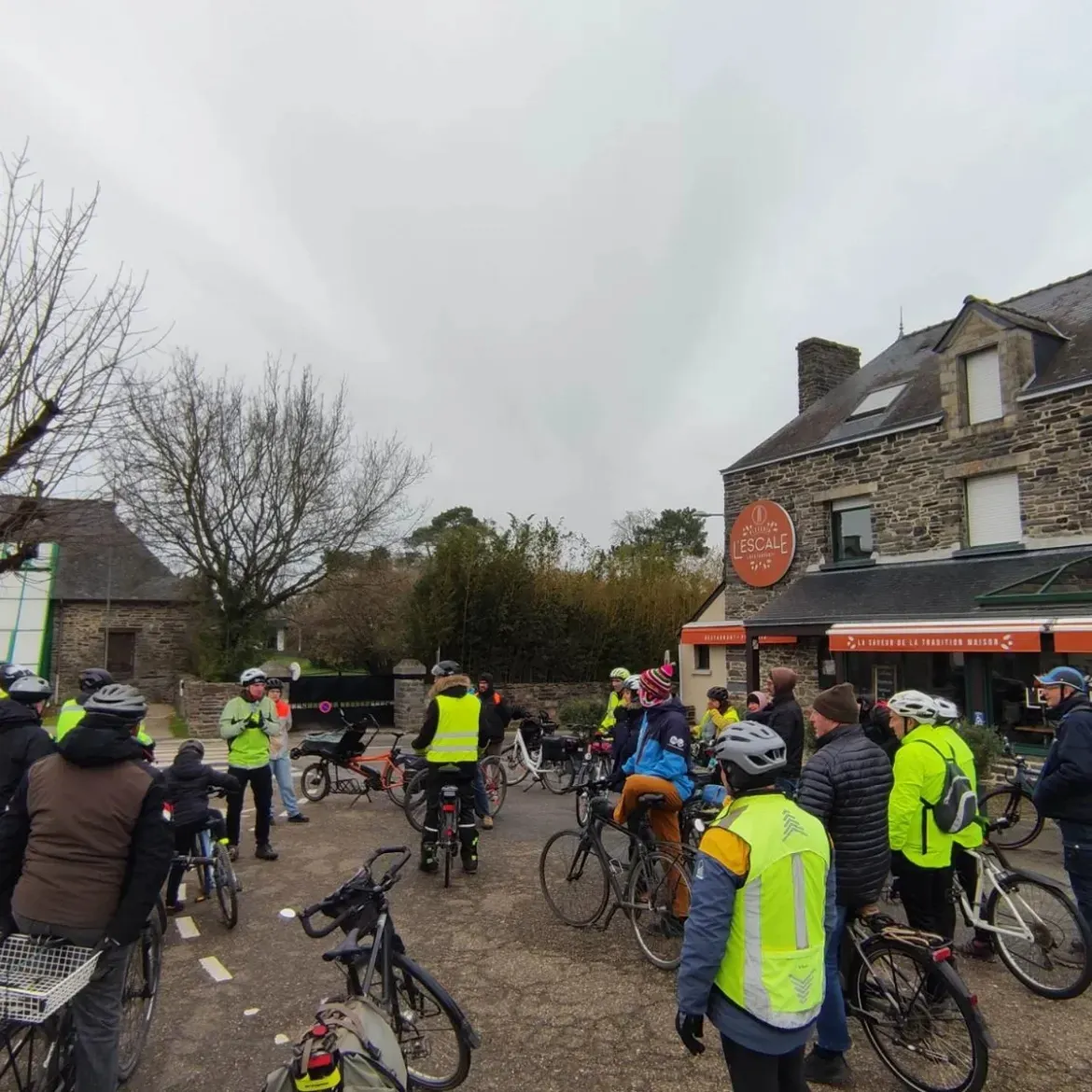 Les cyclistes arrêtés devant les maisons en pierre du centre-bourg