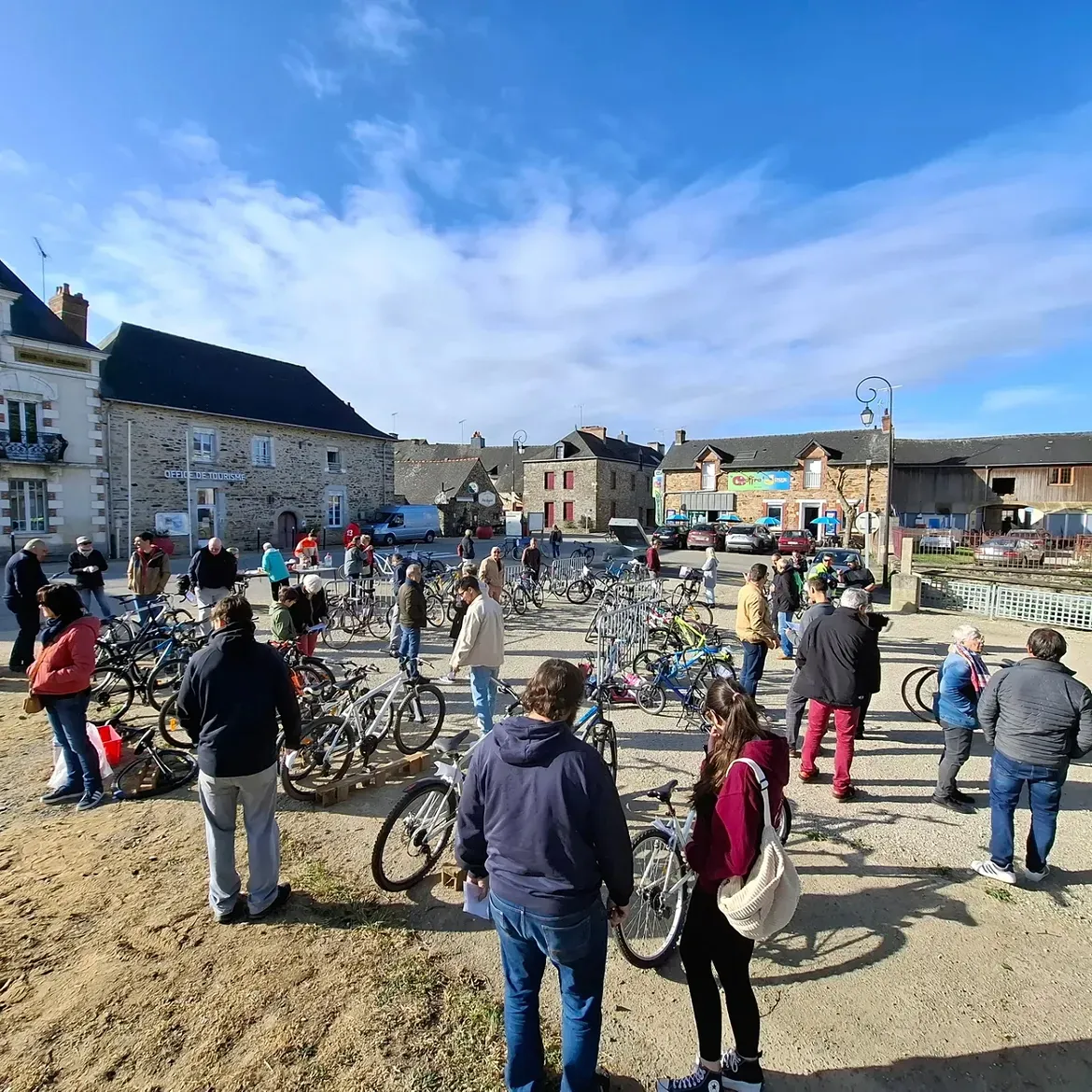 Une place de Guipry-Messac sous le soleil, des vélos alignés et de nombreux visiteurs à la bourse aux vélos