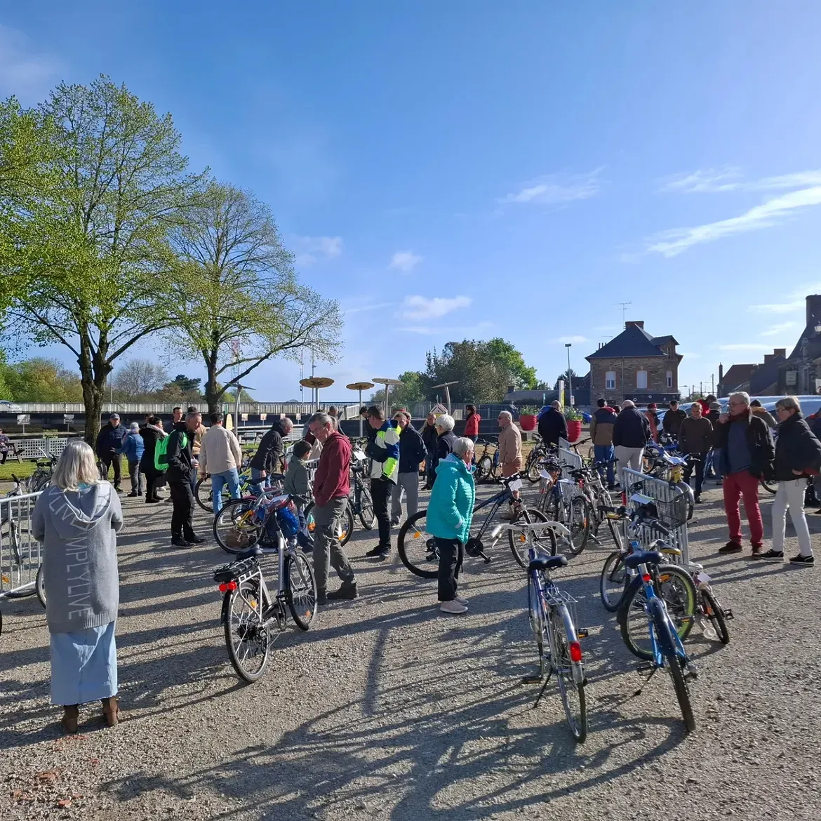 Des visiteurs entre les vélos exposés sur le gravier du square