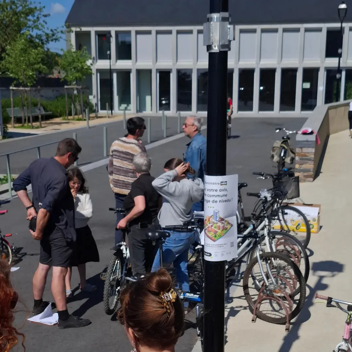 Des visiteurs discutent autour des vélos, une affiche accrochée à un lampadaire