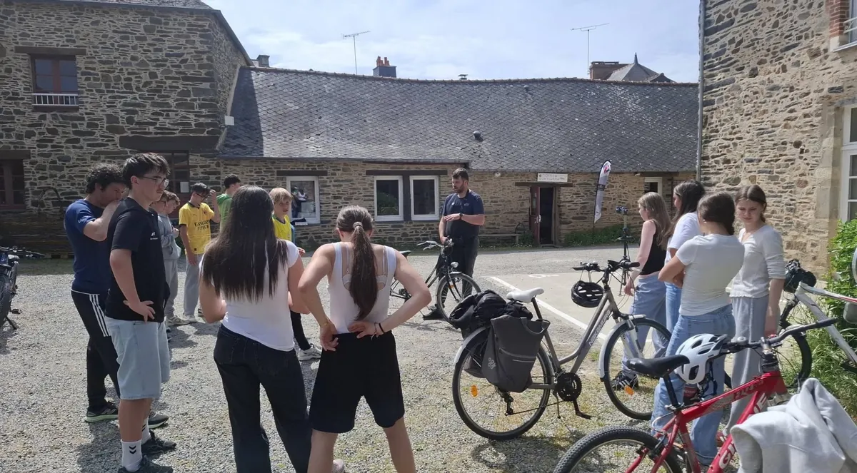 Les élèves et leurs vélos rassemblés dans une cour, devant un bâtiment en pierre