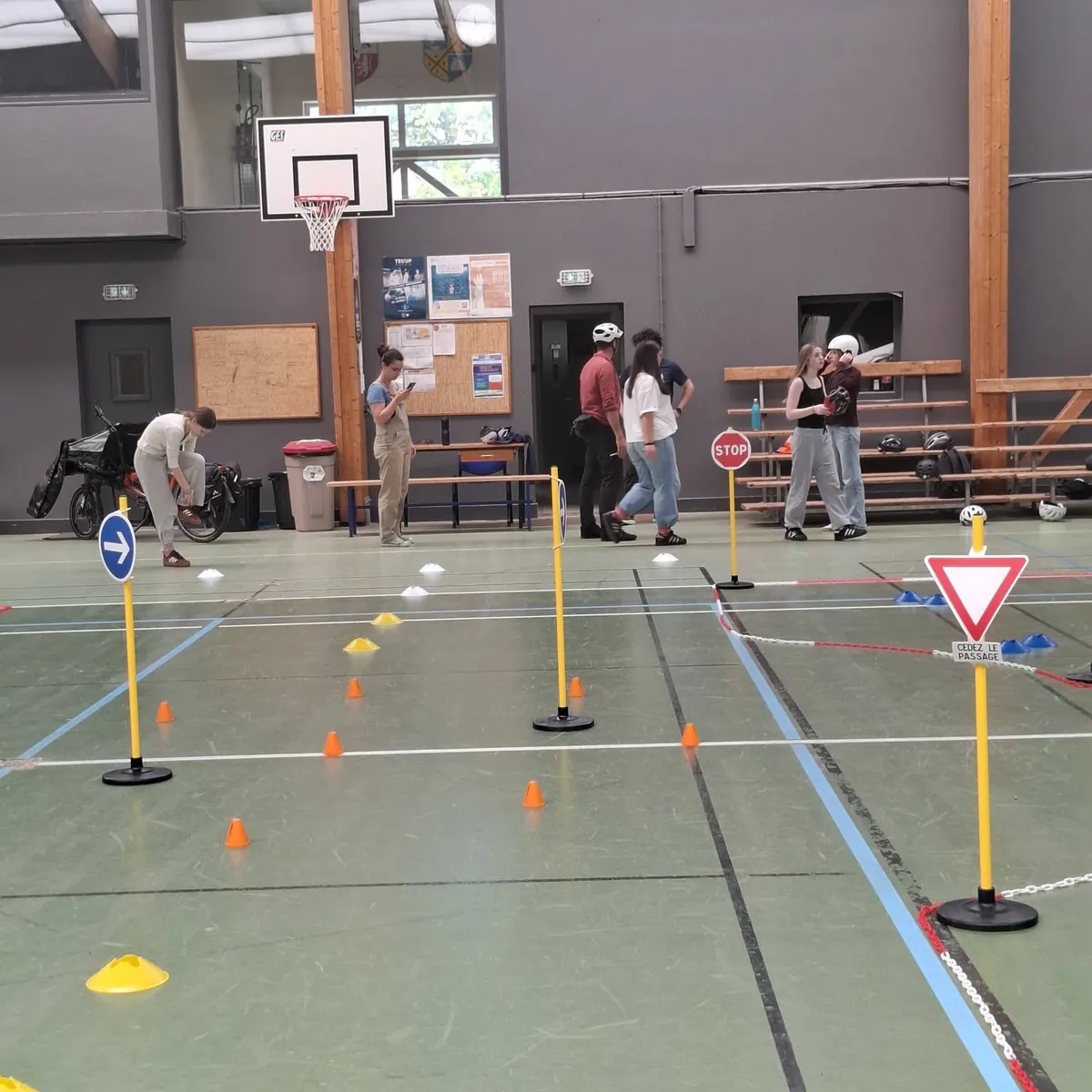 Un parcours de maniabilité dans un gymnase, avec plots, piquets et panneaux de signalisation