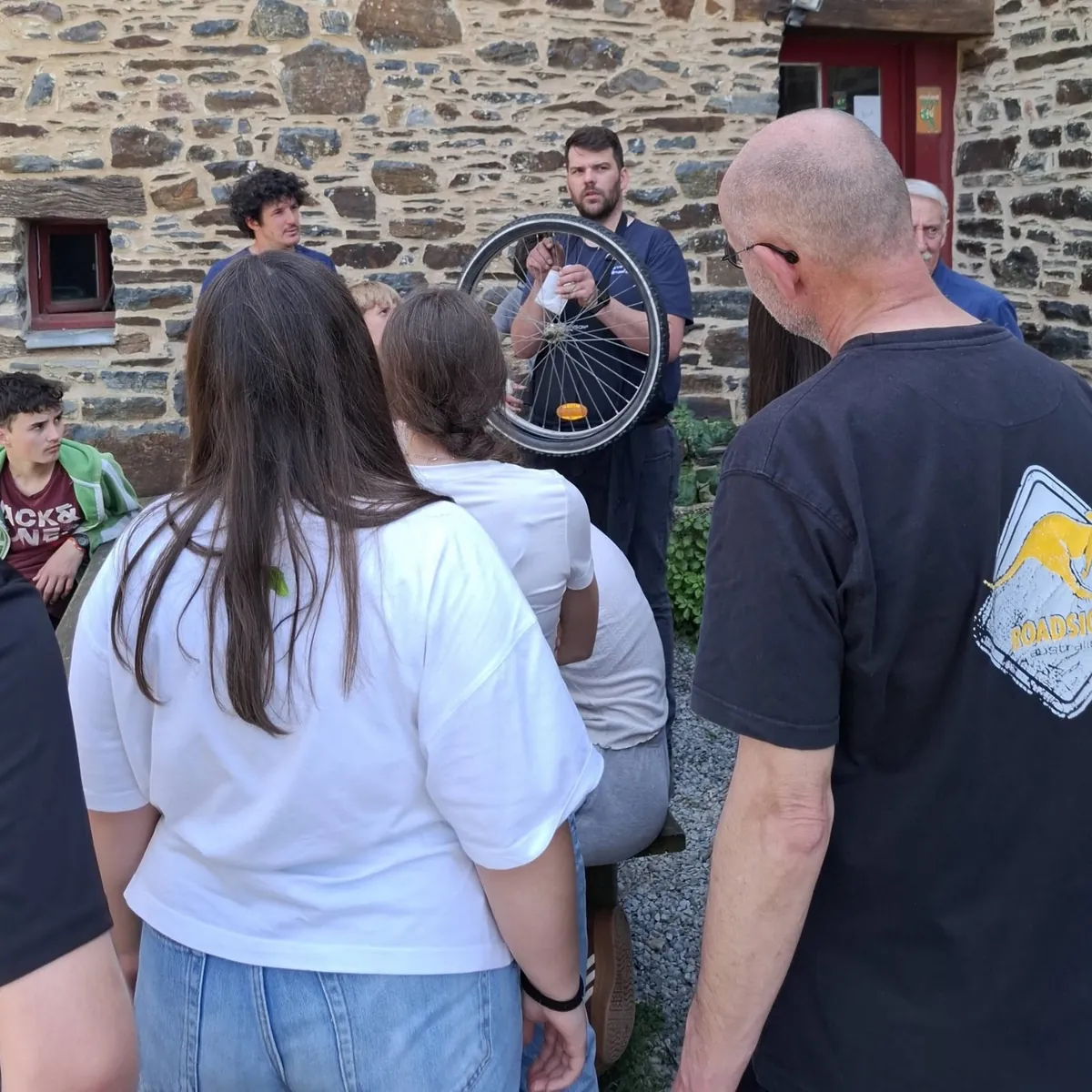 Un bénévole montre une roue de vélo à un groupe d'élèves attentifs