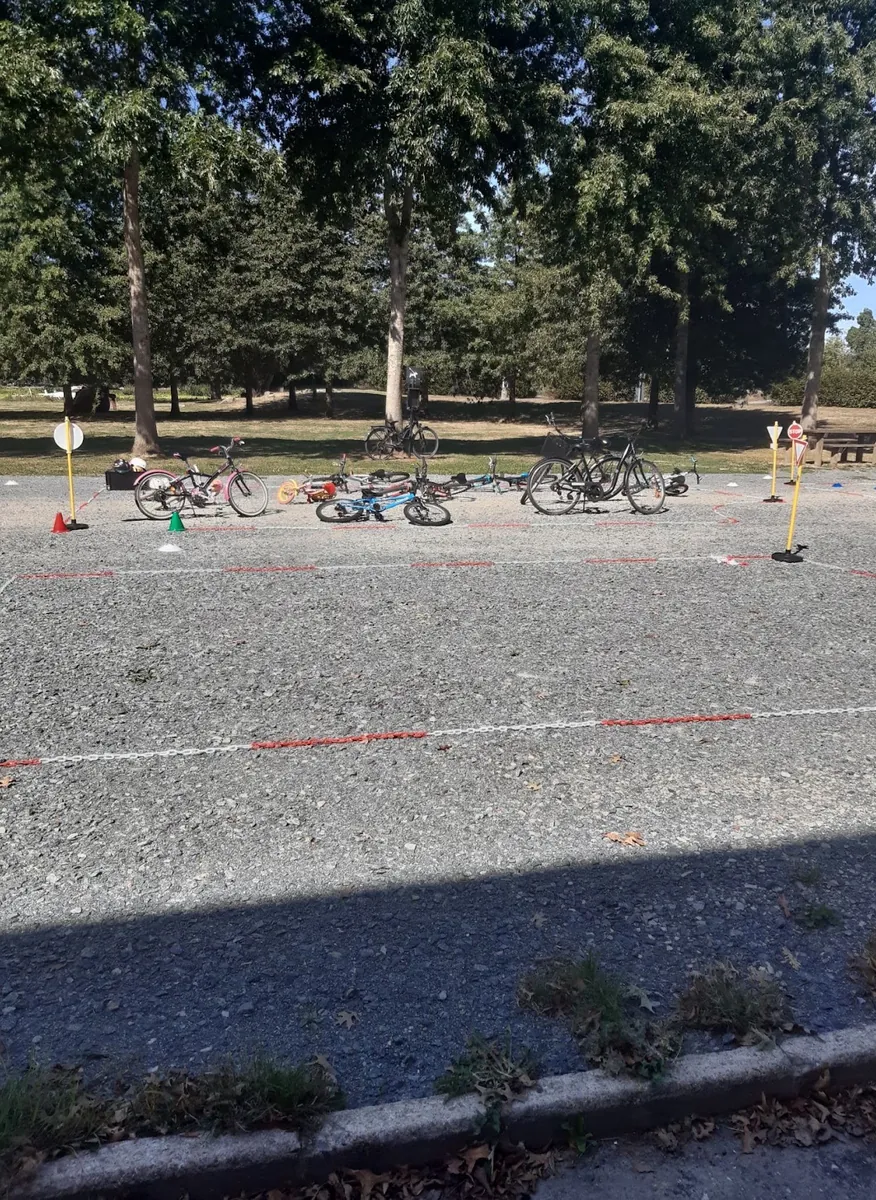 Un parcours tracé à la rubalise sur le gravier, des vélos couchés au fond sous les arbres